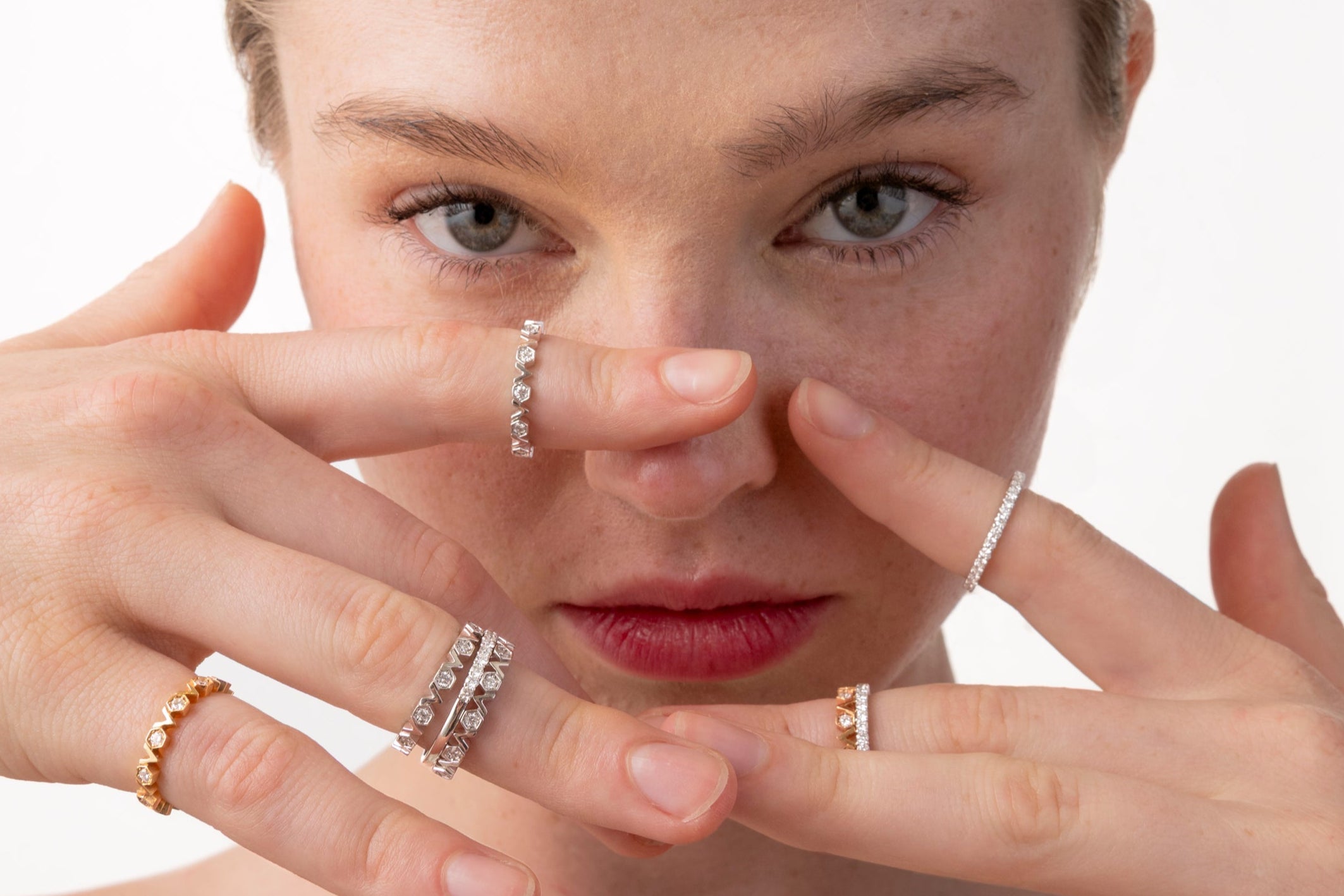 Woman wearing multiple rings on fingers with a plain background